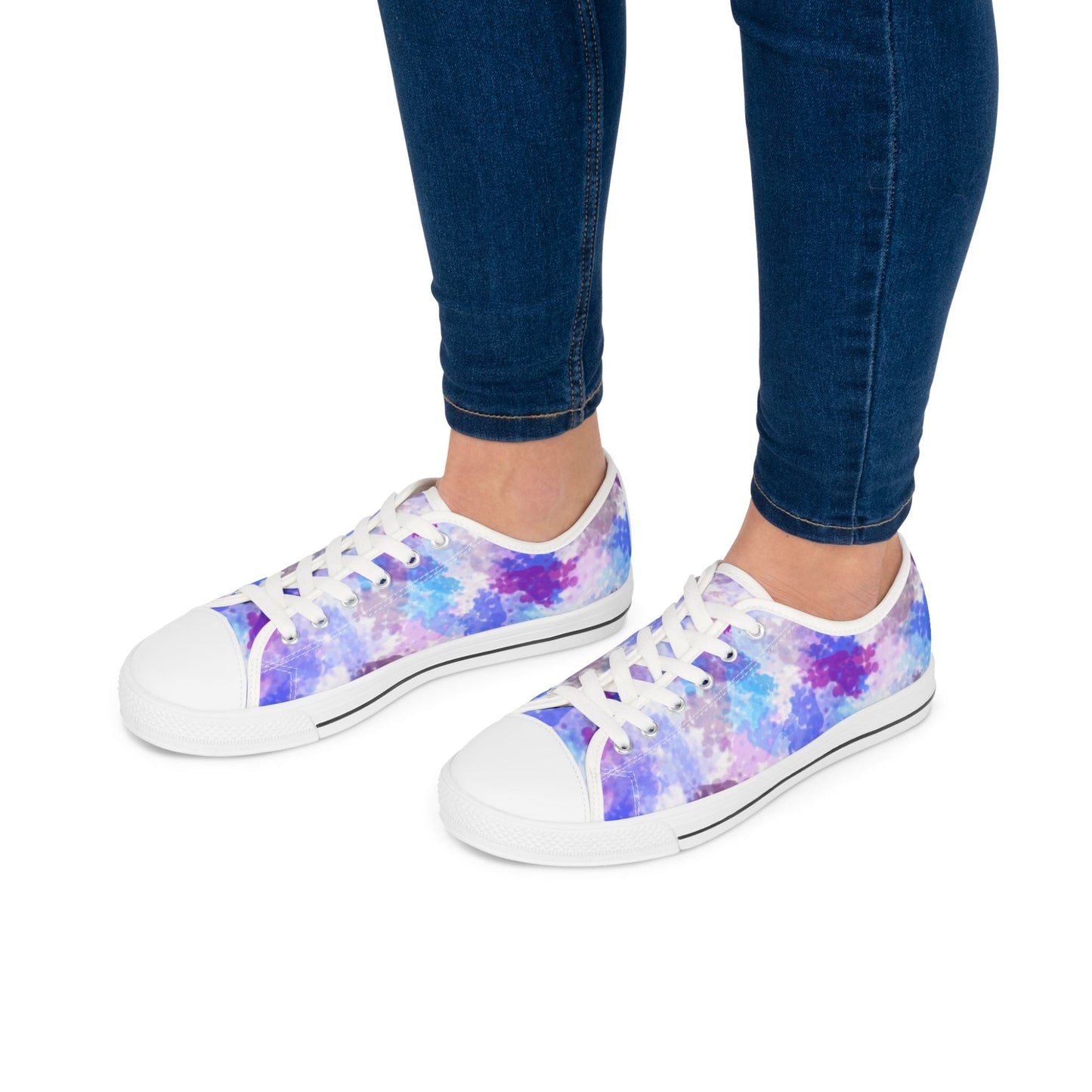 Vibrant women's low top sneakers with colorful abstract design and white soles worn with blue jeans